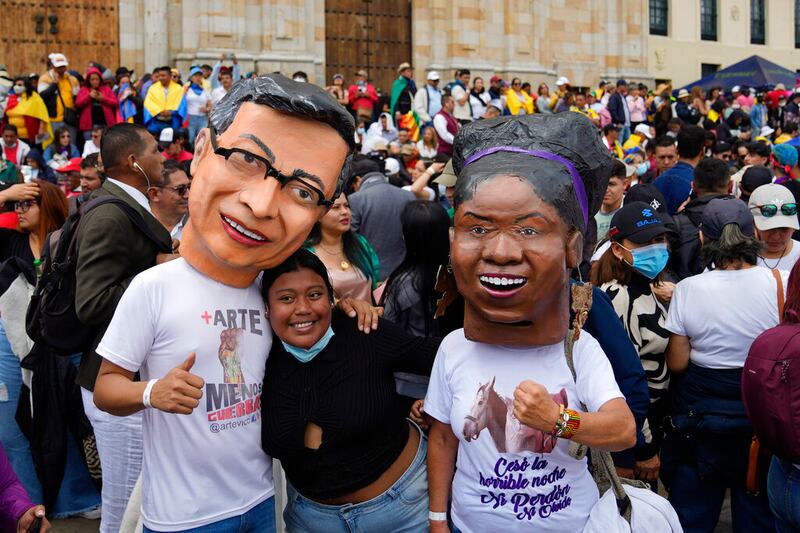 Partidarios del nuevo presidente Gustavo Petro, con máscaras de él y de la nueva vicepresidenta Francia Márquez, a la derecha, esperan la ceremonia de juramentación en la plaza de Bolívar en Bogotá, Colombia.