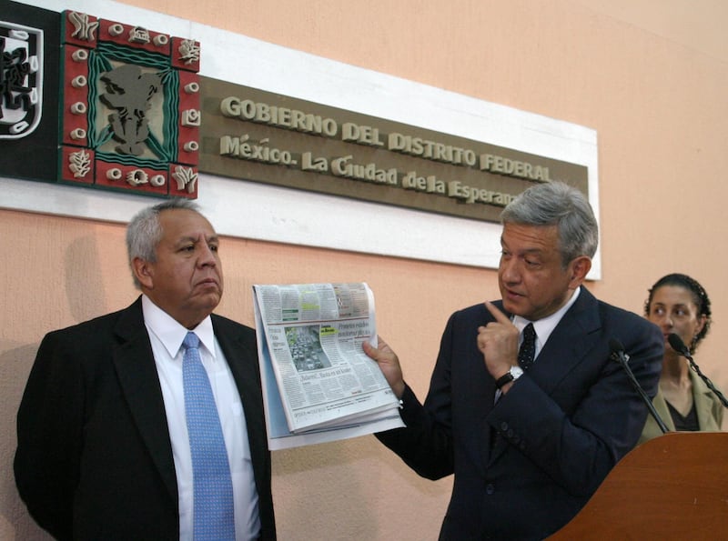 Francisco Garduño, titular de la SETRAVI, Andrés Manuel López Obrador, jefe de Gobierno capitalino, y Claudia Sheinbaun, secretaria del Medio Ambiente en el D.F., durante la conferencia matutina en la sala Francisco Zarco. El mandatario local muestra una fotografía del metrobus publicada en un diario de circulación nacional.