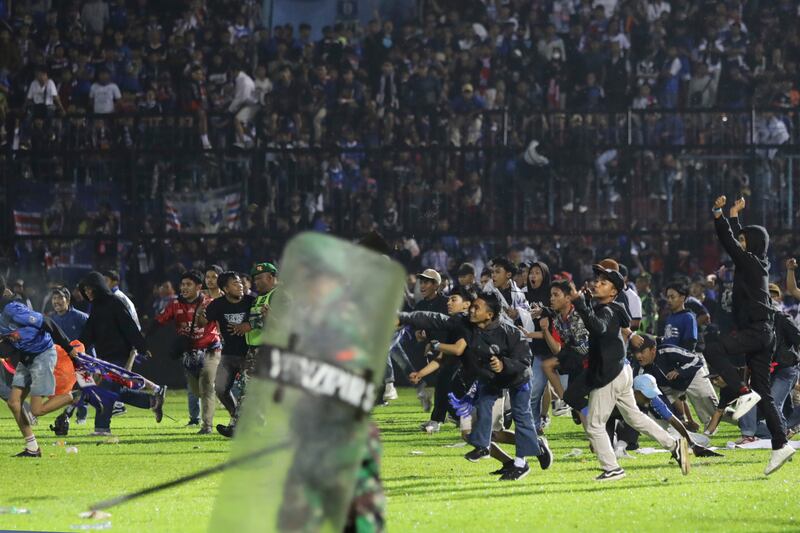 Aficionados al fútbol corren durante una serie de enfrentamientos en Indonesia