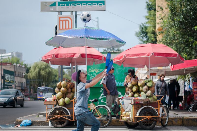 CIUDAD DE MÉXICO, 03NOVIEMBRE2018.- Para ganar dinero, un joven realiza malabares con sus clavas, una sombrilla y un balón de fútbol en el cruce de la calle Heroes y el eje 1 Norte de la colonia Guerrero.