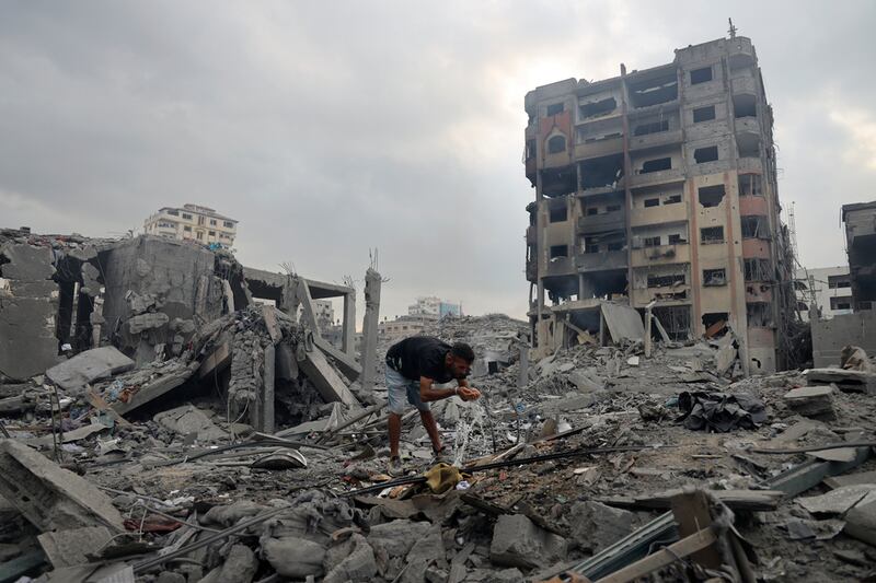 Franja de Gaza, Palestina, 10 de octubre de 2023. Un hombre toma agua de una tubería rota entre edificios destruidos en Gaza después del comienzo de la guerra entre Israel y Hamás.