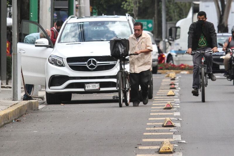 Una camioneta obstruye la ciclovía de Insurgentes, lo que obliga a ciclista a bajar de la bicicleta y a otro más invadir el carril de autos. Foto: Cuartoscuro