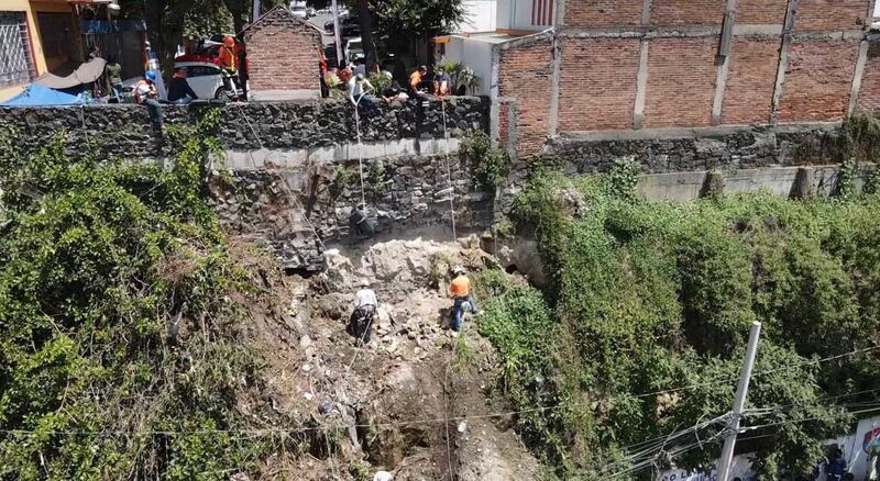 Personal de la alcaldía Álvaro Obregón colocan una membrana plástica como medida de mitigación en el talud.