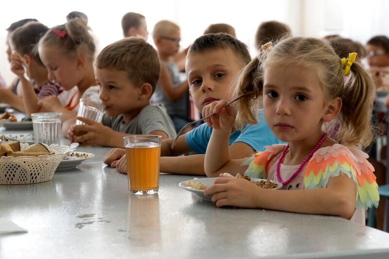 Niños de orfanatos de la región de Donetsk durante el almuerzo en un campamento de Zolotaya Kosa, sobre el mar de Azov, el 8 de julio del 2022.