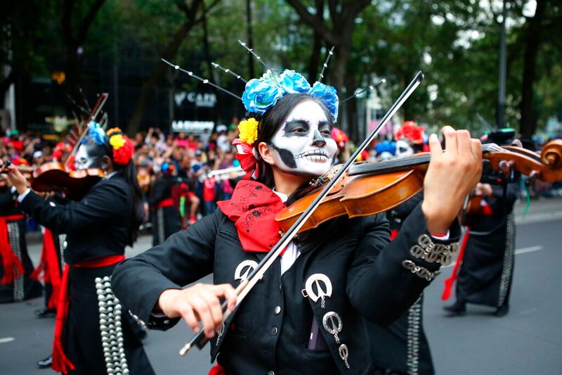 Una mujer toca el violín mientras participa con otros en el desfile del Día de los Muertos en Ciudad de México, el sábado 29 de octubre de 2022. El desfile está inspirado en la película de Bond de 2015 "Spectre" y se ha convertido en un evento en la Ciudad de México con miles de personas desfilando entre carrozas gigantes, música y disfraces. (AP Photo/Ginnette Riquelme)