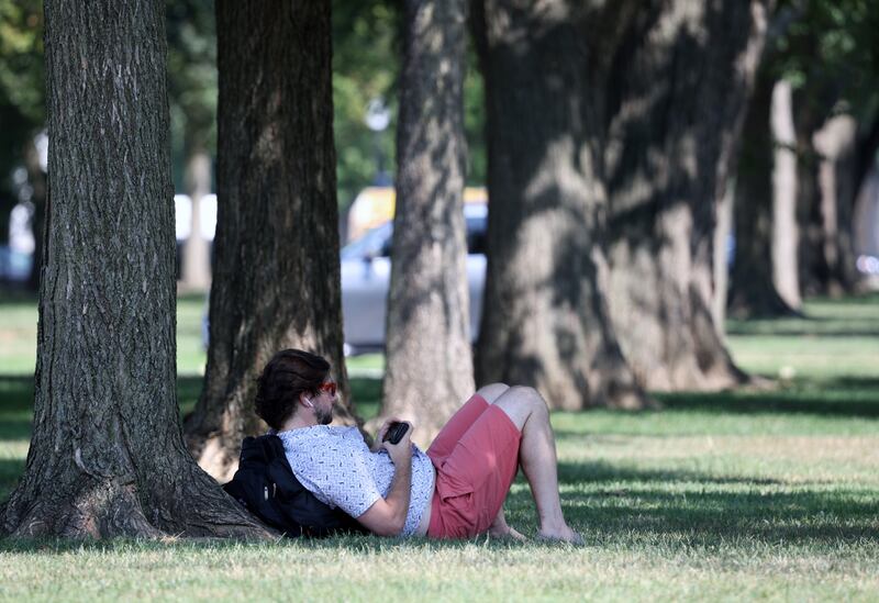 WASHINGTON, DC - 12 DE AGOSTO: Una persona se relaja a la sombra de un árbol en el National Mall mientras las temperaturas alcanzan los 97 grados fahrenheit el 12 de agosto de 2021 en Washington, DC. Un informe sobre el clima publicado recientemente por las Naciones Unidas predice que el mundo seguirá calentándose y que las olas de calor, las inundaciones y los incendios devastadores serán cada vez más frecuentes.