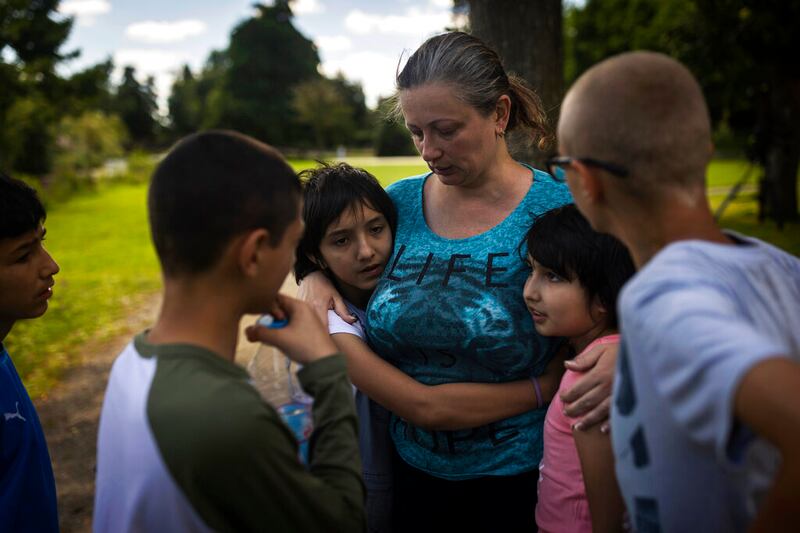 Olga Lopatkina abraza a sus hijos adoptivos en un parque de Loue (Francia). Se separó de los chicos en medio de la guerra en Ucrania y los niños fueron llevados a Rusia. Luego de arduas negociaciones logró reunirse nuevamente con ellos.