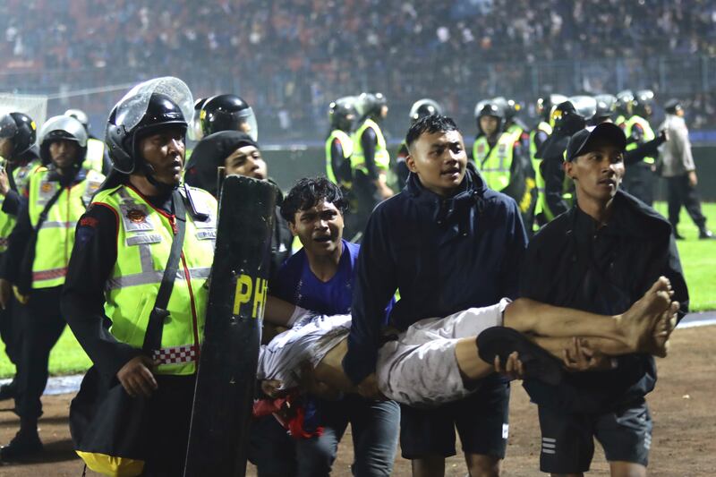 Aficionados cargan a un hombre herido en los enfrentamientos durante un partido de fútbol en Malang, Indonesia.