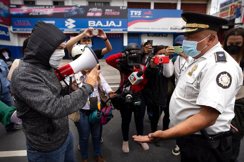 Un estudiante enmascarado habla con la policía durante una protesta antigubernamental que bloquea una carretera cerca de la universidad pública de San Carlos en la Ciudad de Guatemala, el martes 9 de agosto de 2022.